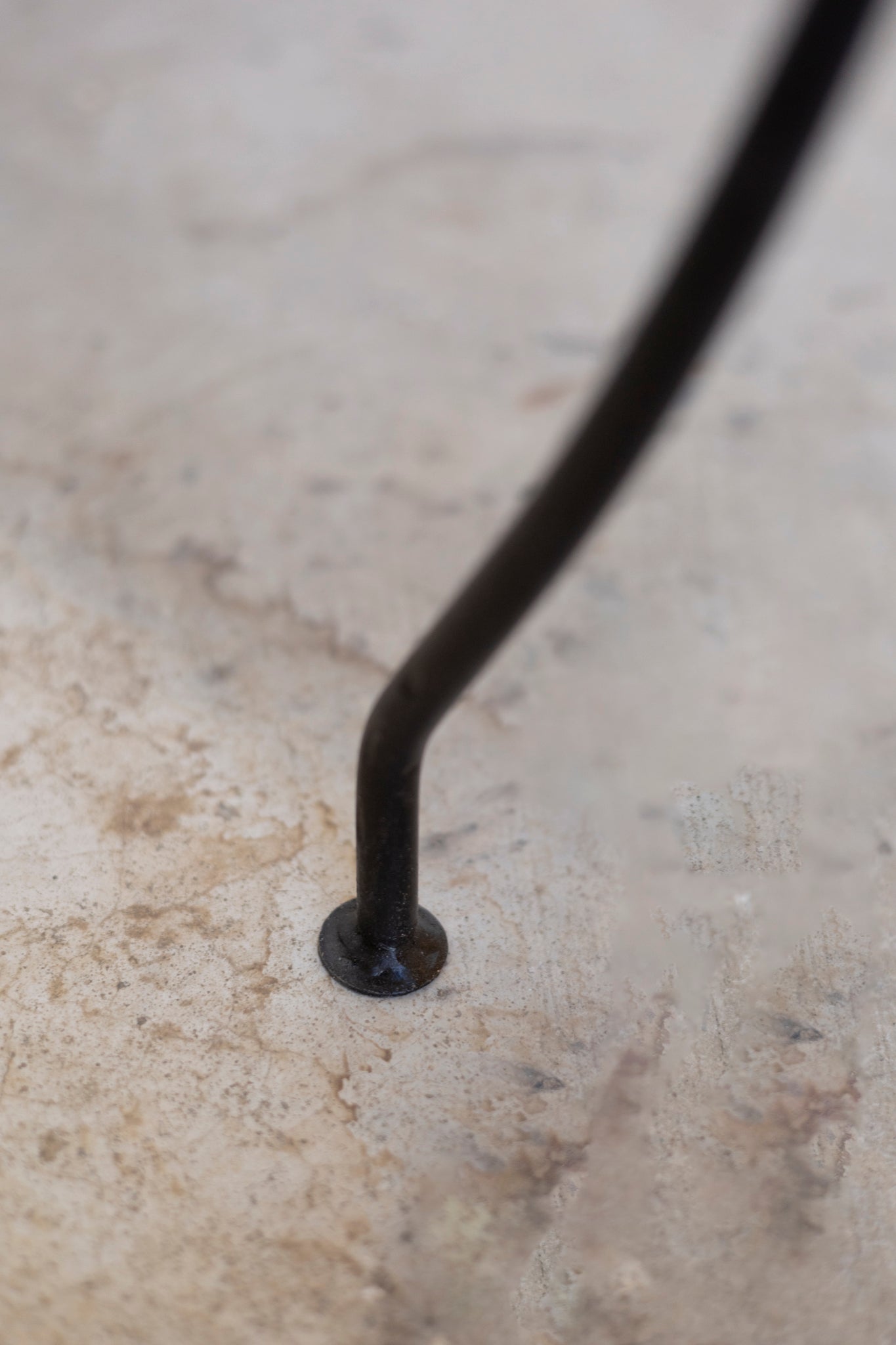 Black metal rod on a textured beige surface