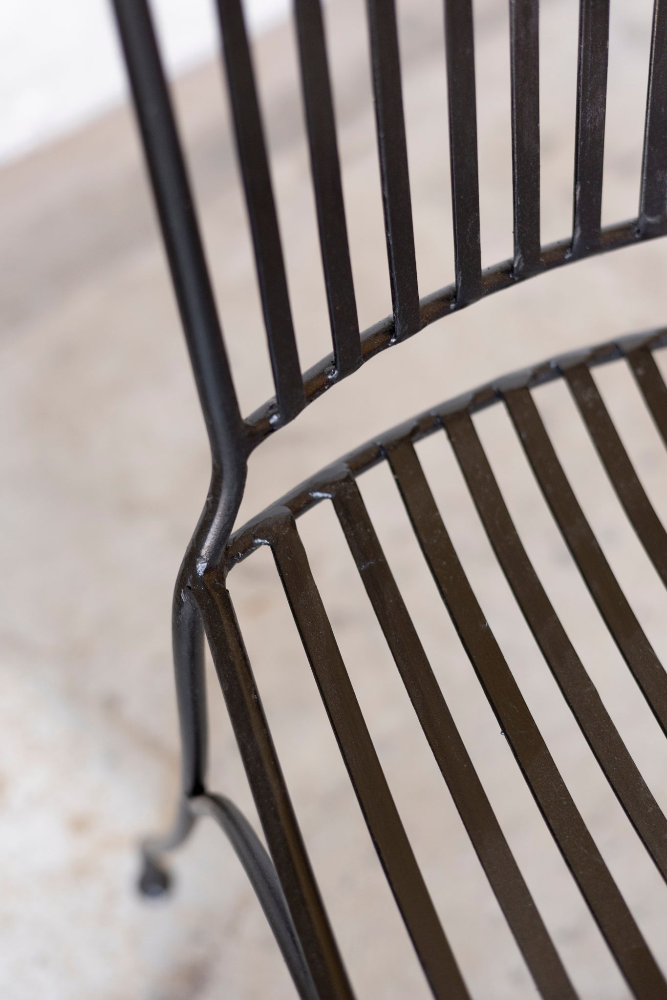 Close-up of a black metal chair with a blurred background