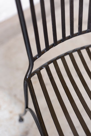 Close-up of a black metal chair with a blurred background