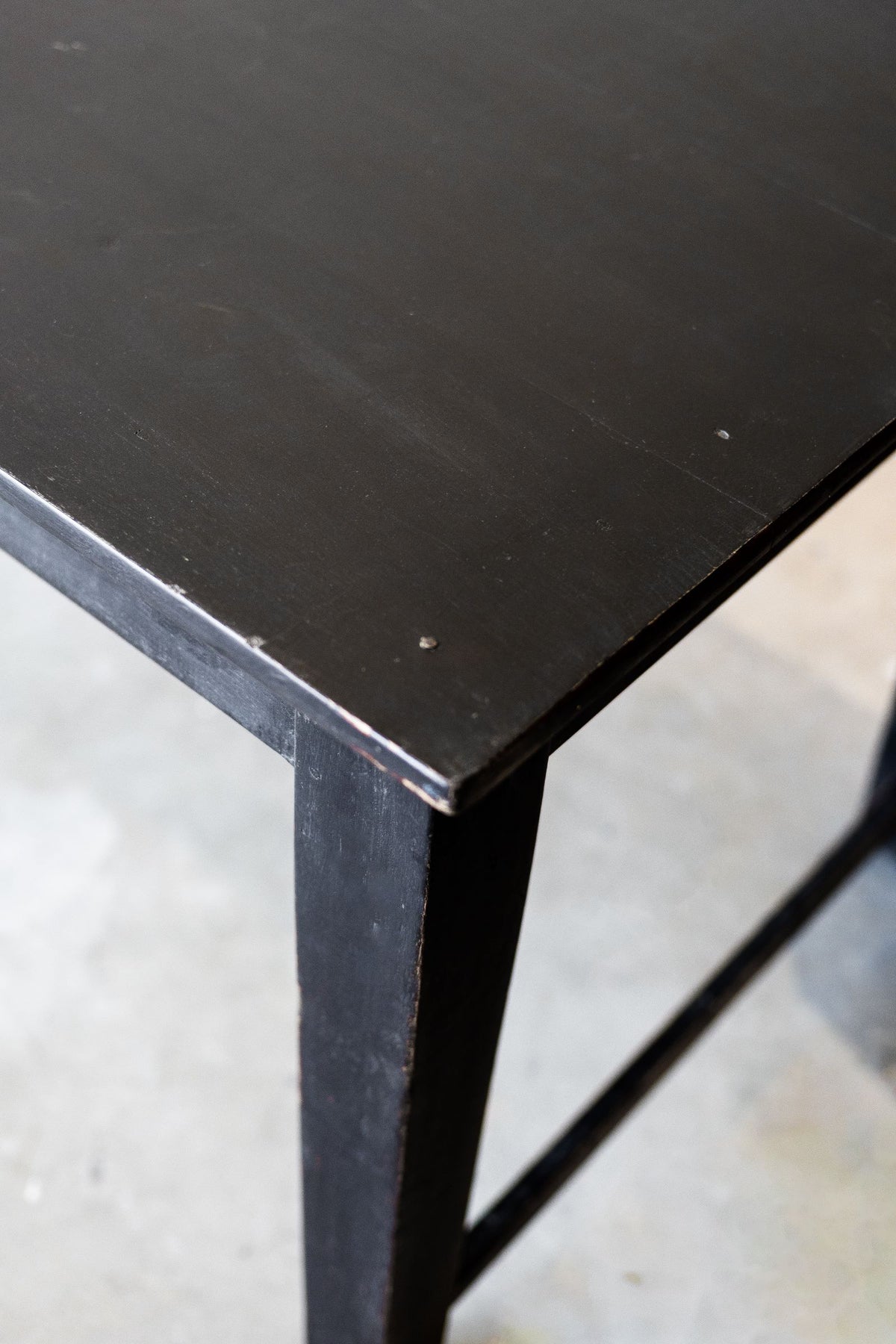 Close-up of a black wood table corner on a light gray floor.