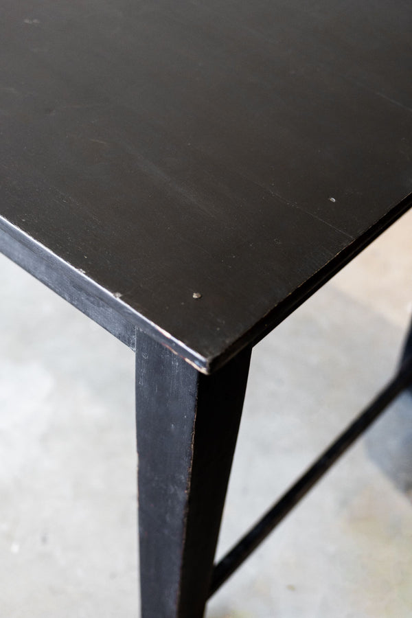 Close-up of a black wood table corner on a light gray floor.
