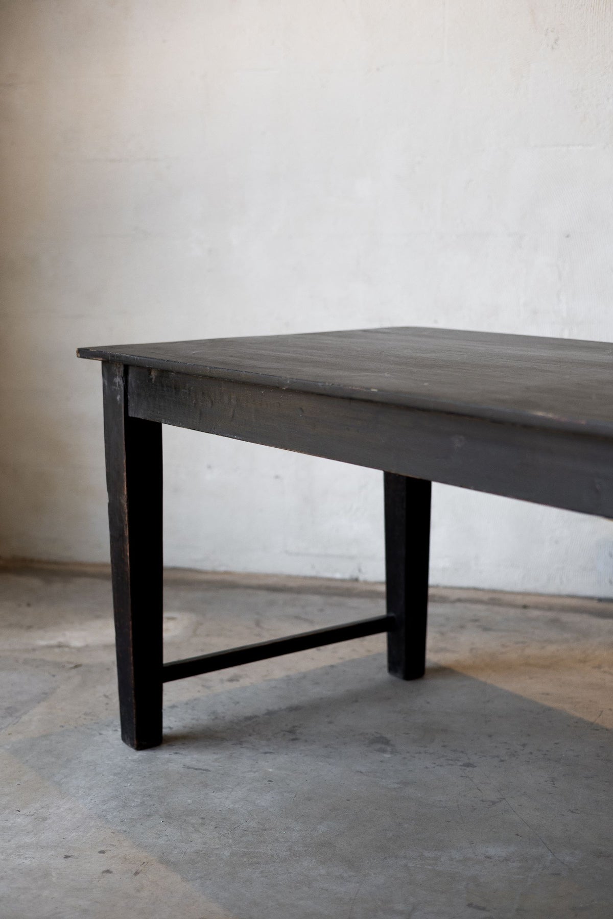 Dark wooden table against a plain wall on a concrete floor