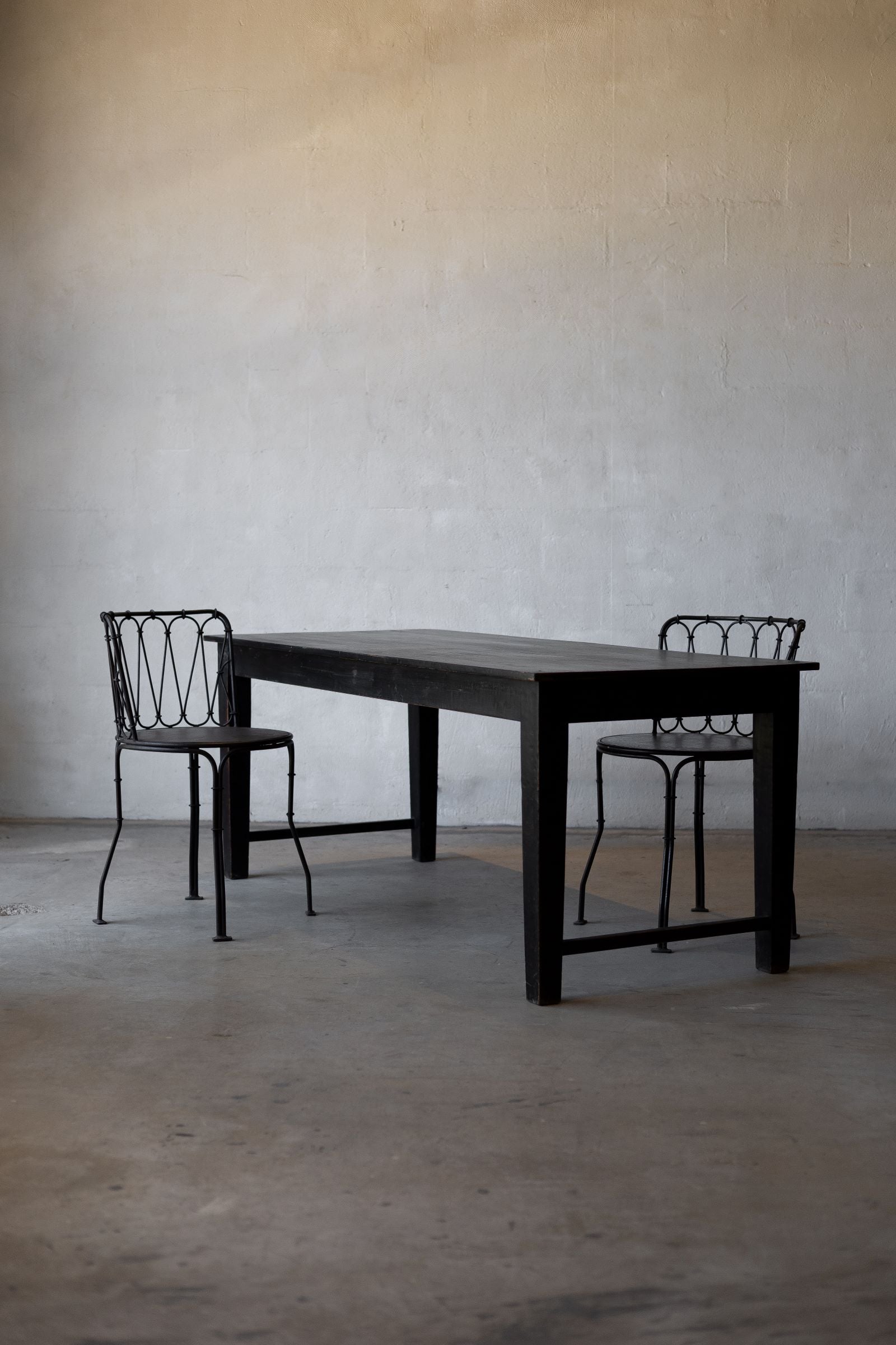 Black table with two matching chairs against a plain wall.