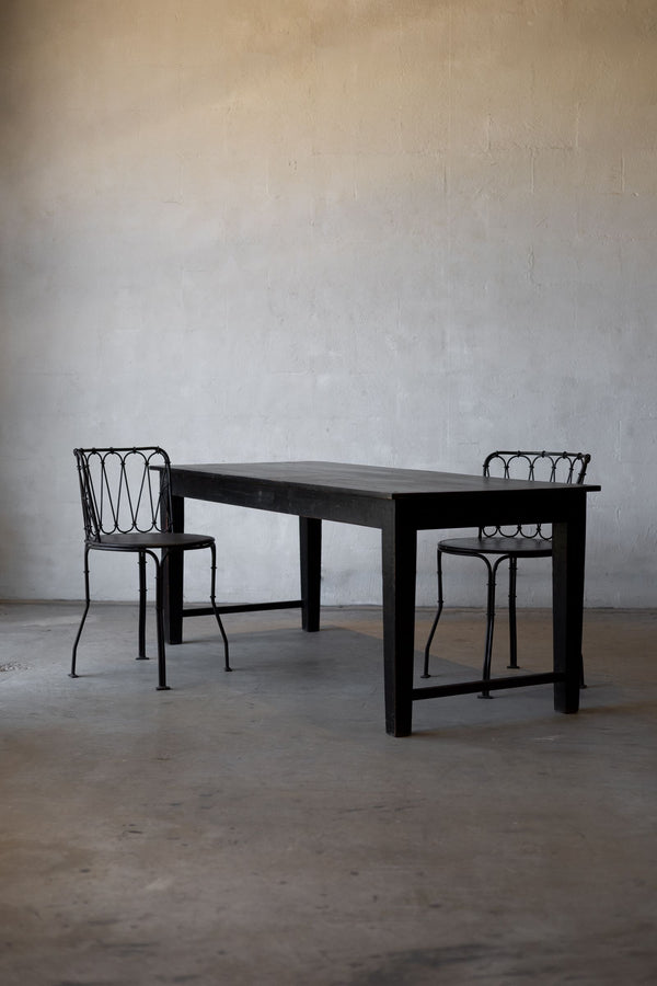 Black table with two matching chairs against a plain wall.