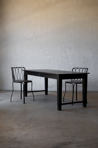 Black table with two matching chairs against a plain wall.