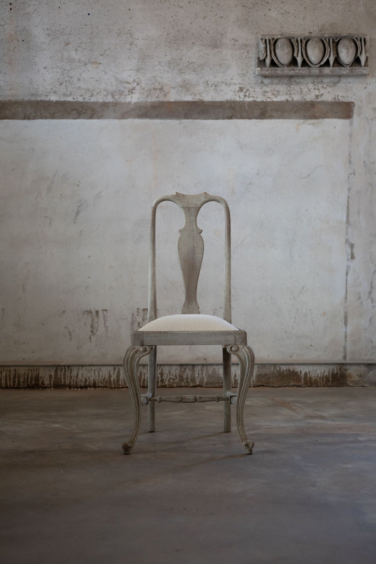 Vintage chair in a room with textured walls and concrete floor Main image