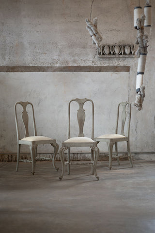 Three vintage-style chairs in a room with textured walls and a chandelier.