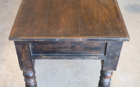 Side of vintage colonial teak wood desk showing wear and tear against a plain background.
