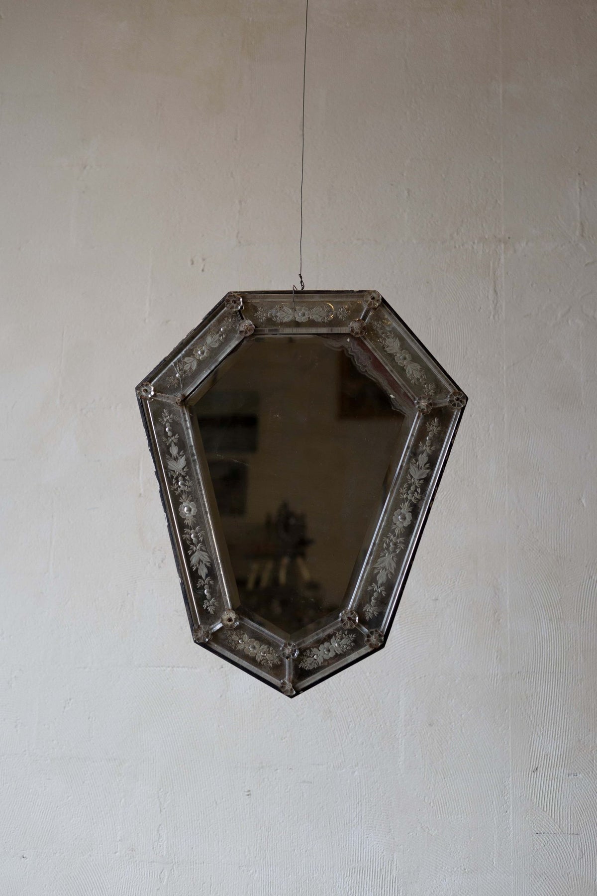 Venetian crystal mirror with shield shape and a beveled glass frame featuring intricate floral etchings.
