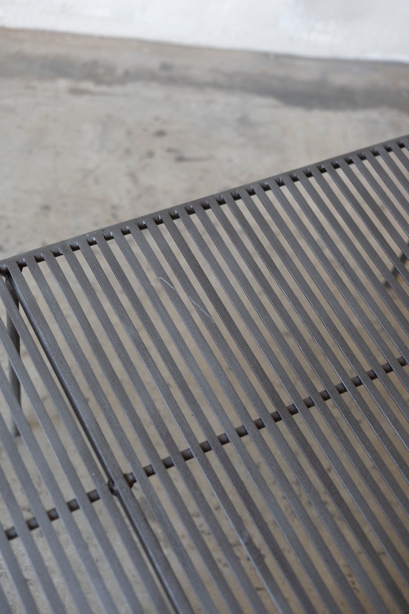 Close-up of a metal grate Wave Coffee Table on a concrete surface