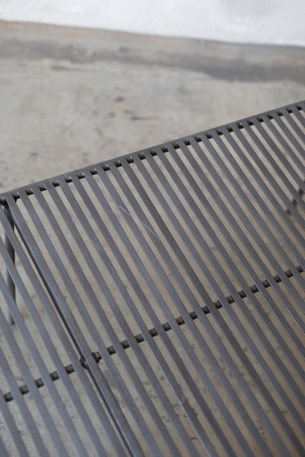 Close-up of a metal grate Wave Coffee Table on a concrete surface
