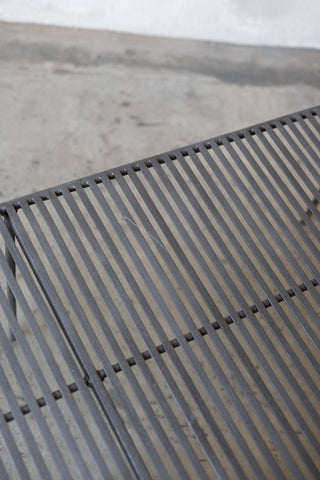 Close-up of a metal grate Wave Coffee Table on a concrete surface