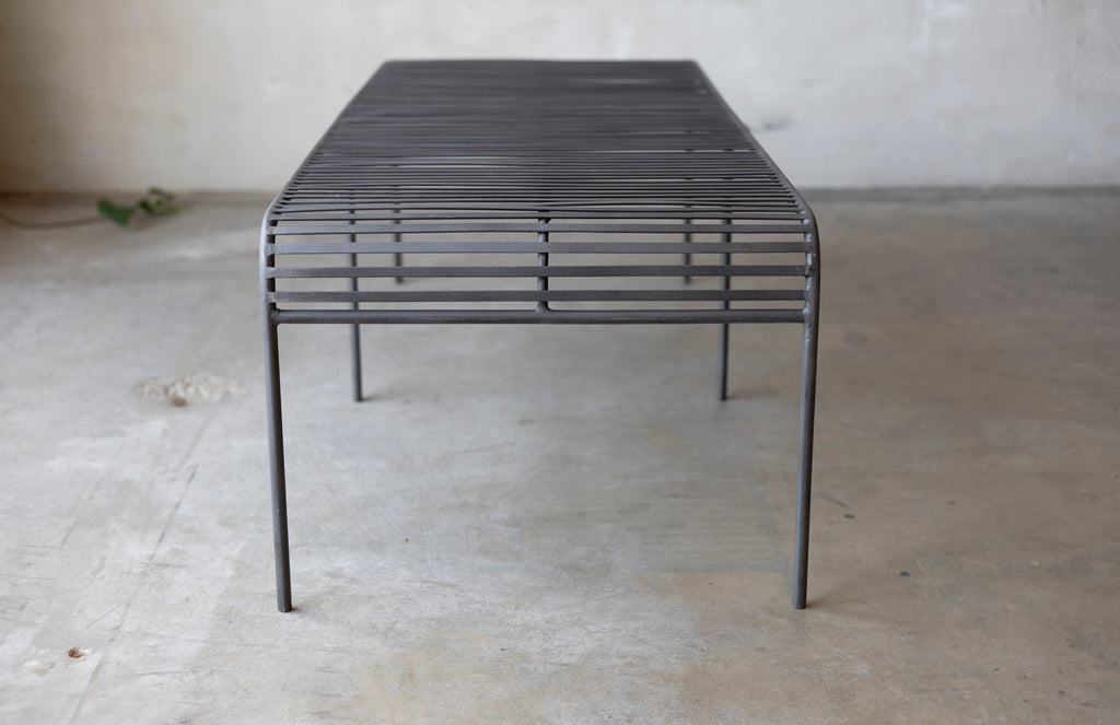 The metal grate Wave Coffee Table on a concrete surface