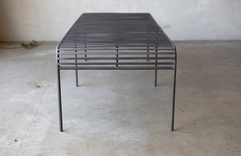 The metal grate Wave Coffee Table on a concrete surface