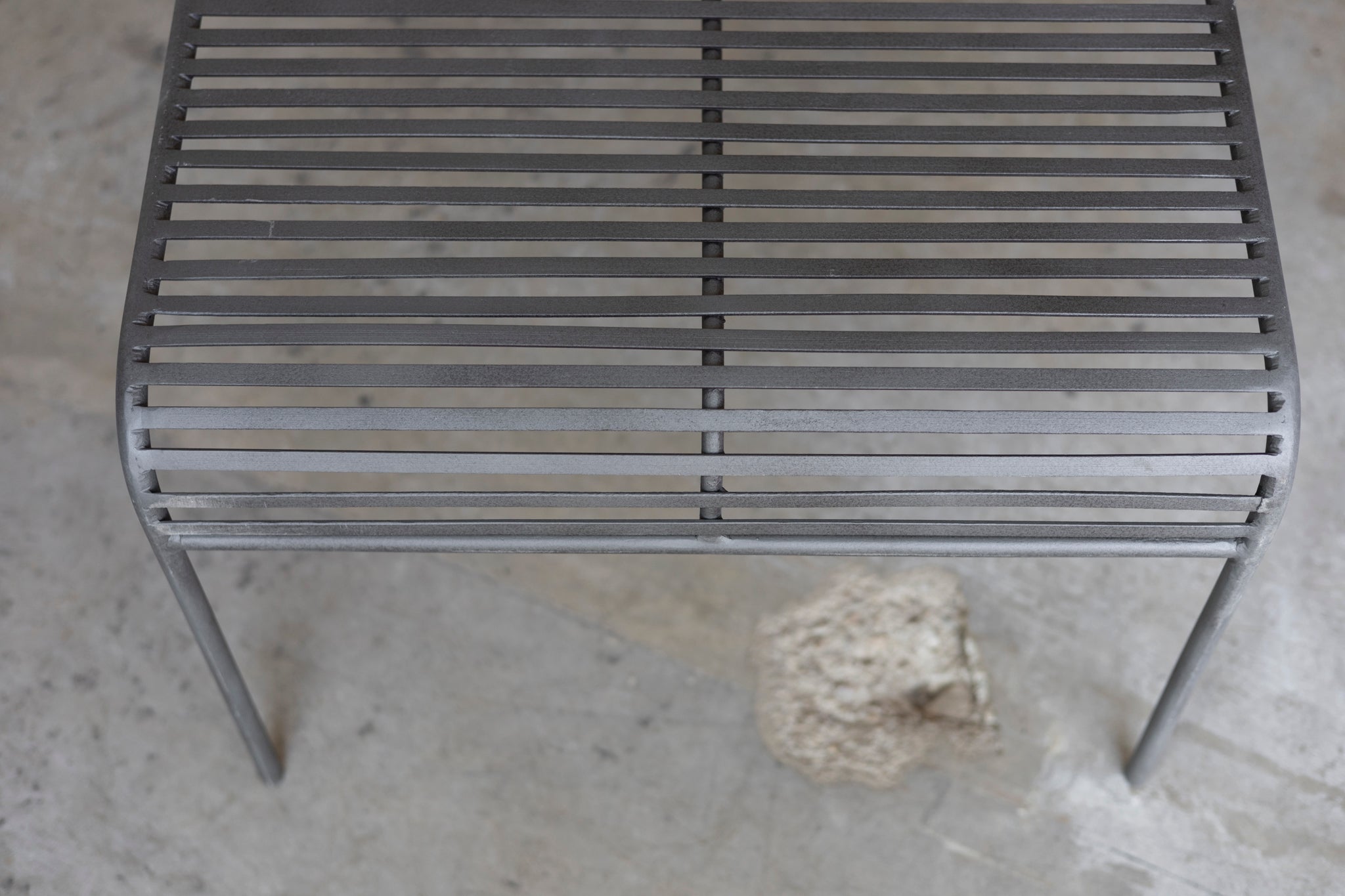 Close-up of a metal grate Wave Coffee Table on a concrete surface