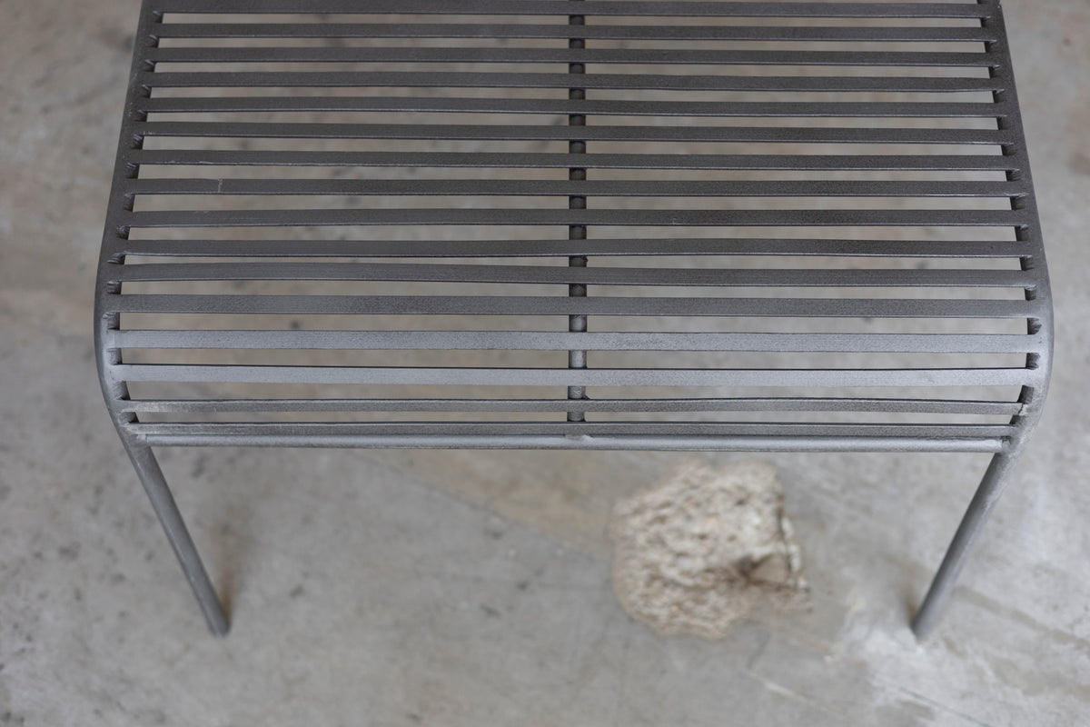 Close-up of a metal grate Wave Coffee Table on a concrete surface
