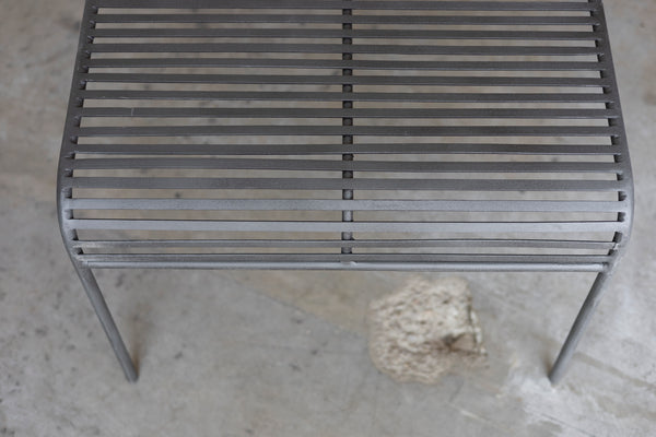Close-up of a metal grate Wave Coffee Table on a concrete surface