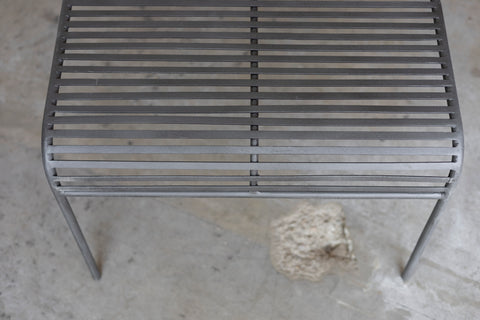 Close-up of a metal grate Wave Coffee Table on a concrete surface