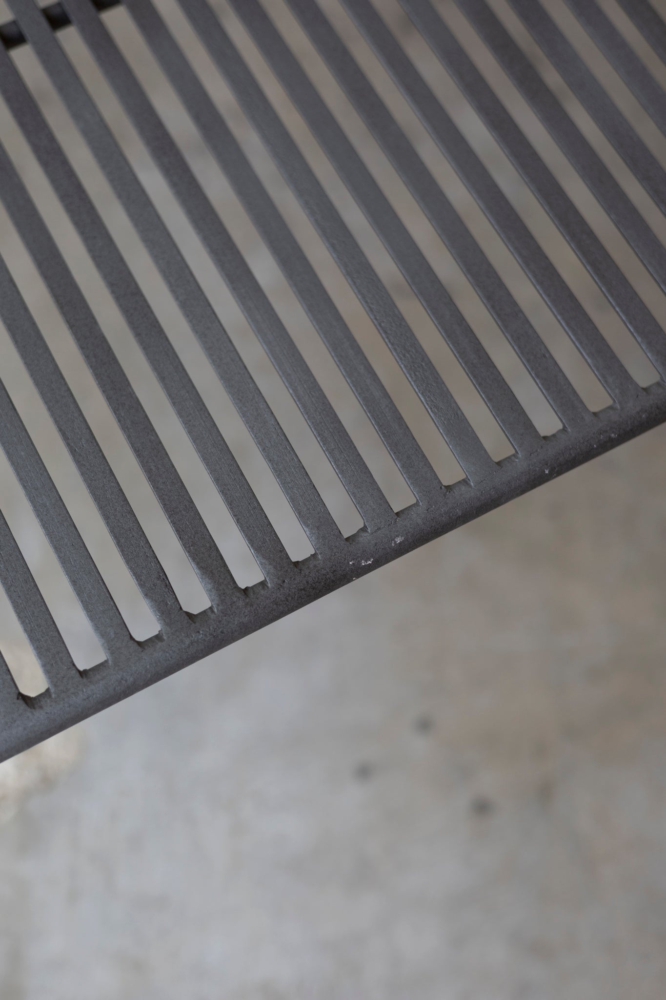 Close-up of a metal grate Wave Coffee Table on a concrete surface