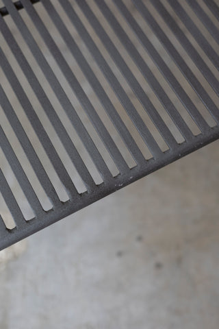 Close-up of a metal grate Wave Coffee Table on a concrete surface