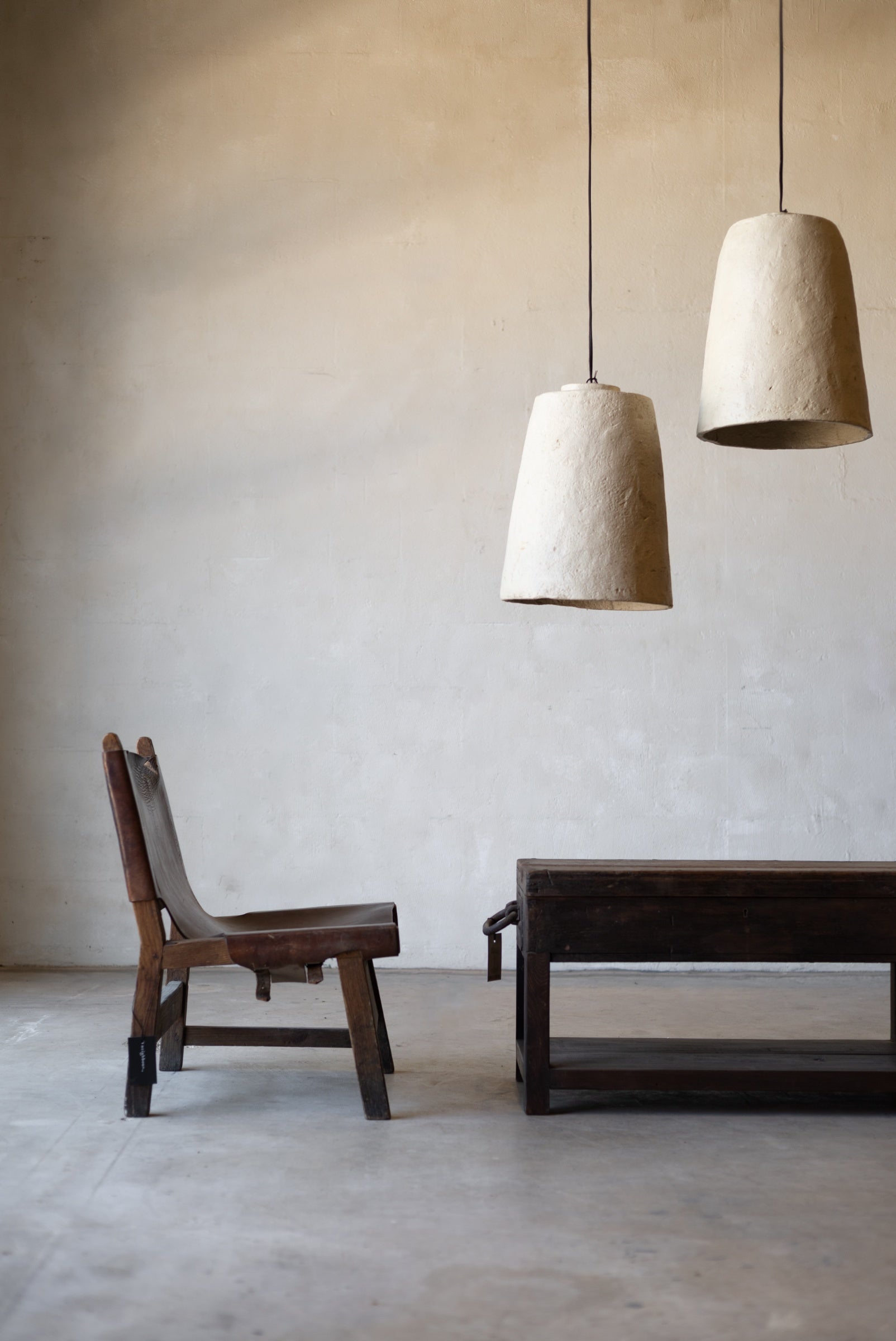 Minimalist interior with wooden chair and table under two white pendant lights.