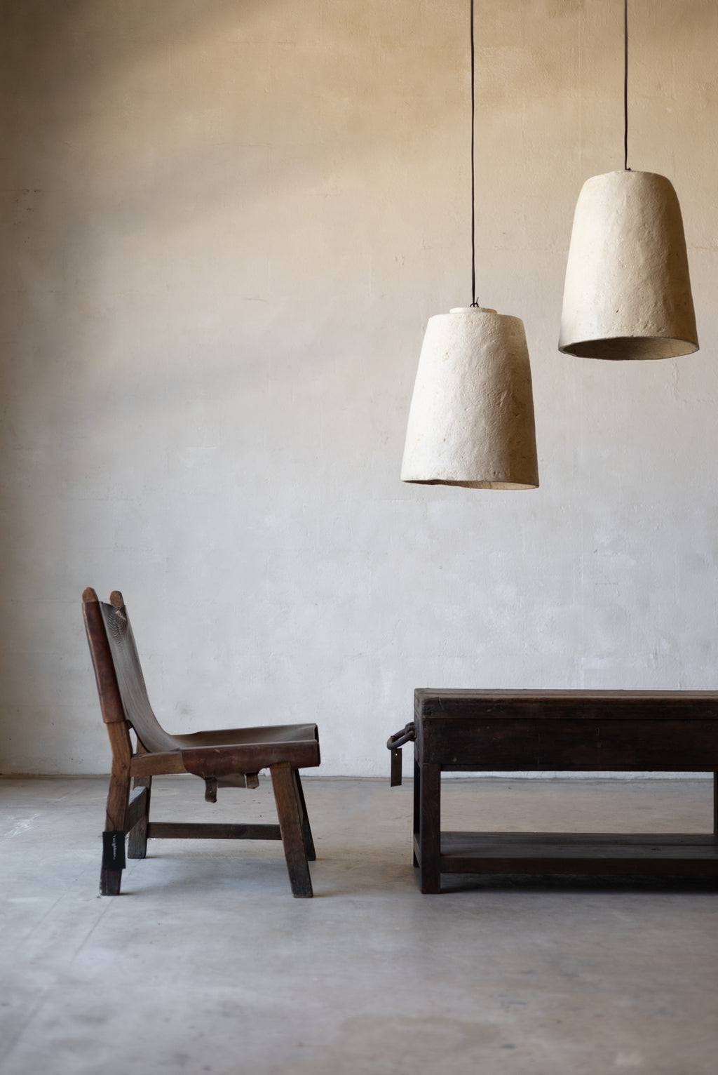 Minimalist interior with wooden chair and table under two white pendant lights.