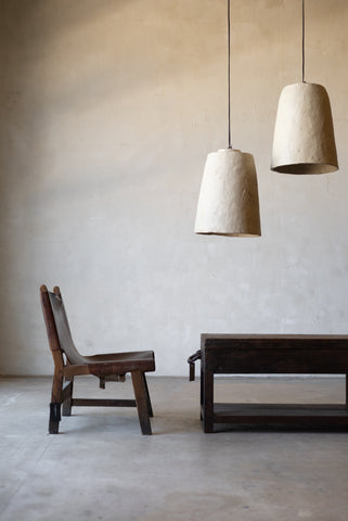 Minimalist interior with wooden chair and table under two white pendant lights.