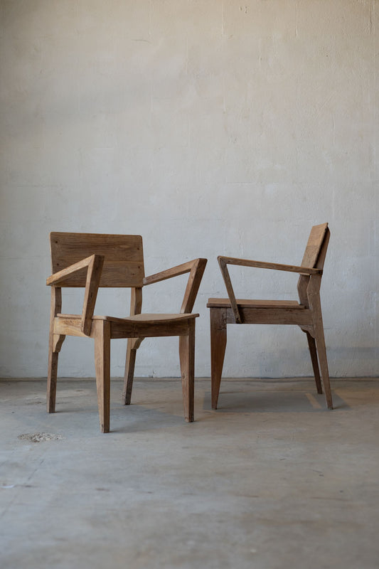 Pair of antique art deco wood dining chairs with angled arm rests.