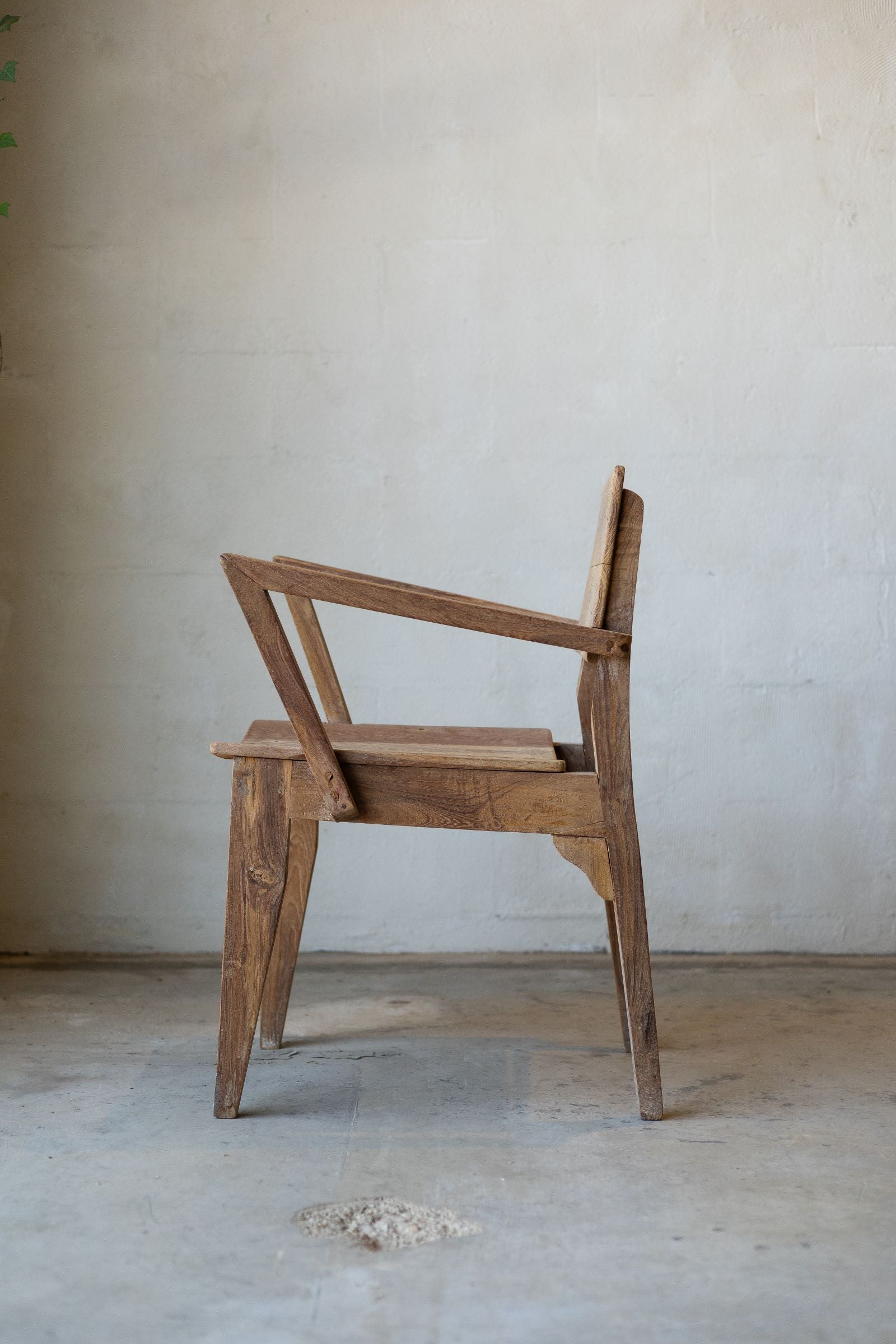 Side profile of antique art deco wood dining chairs with angled arm rests.