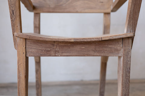 Close up of seat of antique art deco wood dining chairs showing curved seat. 