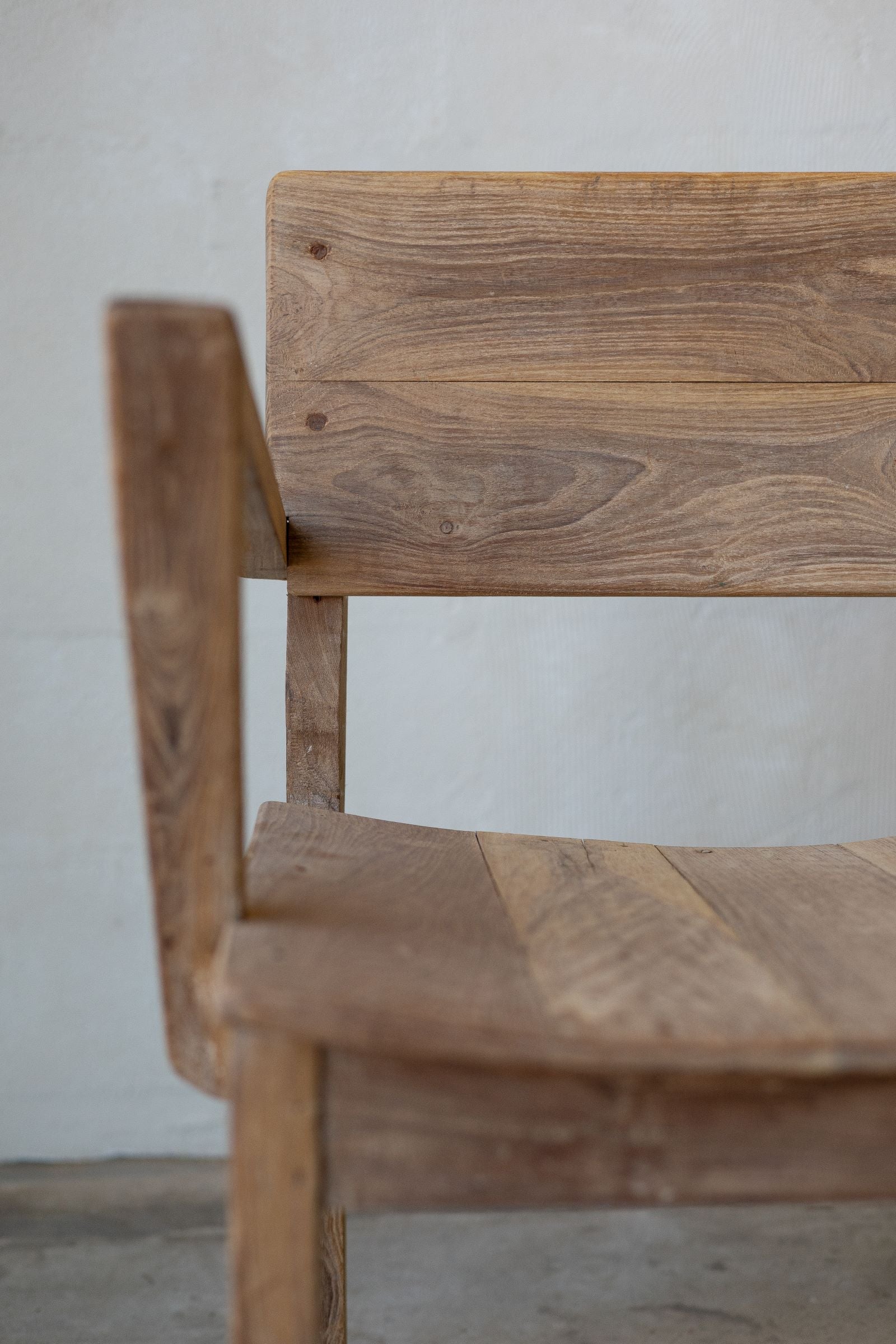 Close up of side of antique art deco wood dining chairs with angled arm rests.