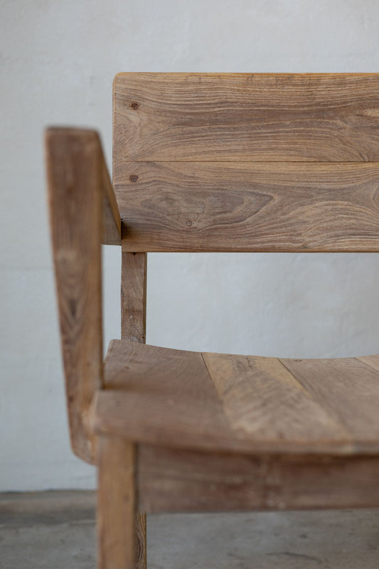 Close up of side of antique art deco wood dining chairs with angled arm rests.