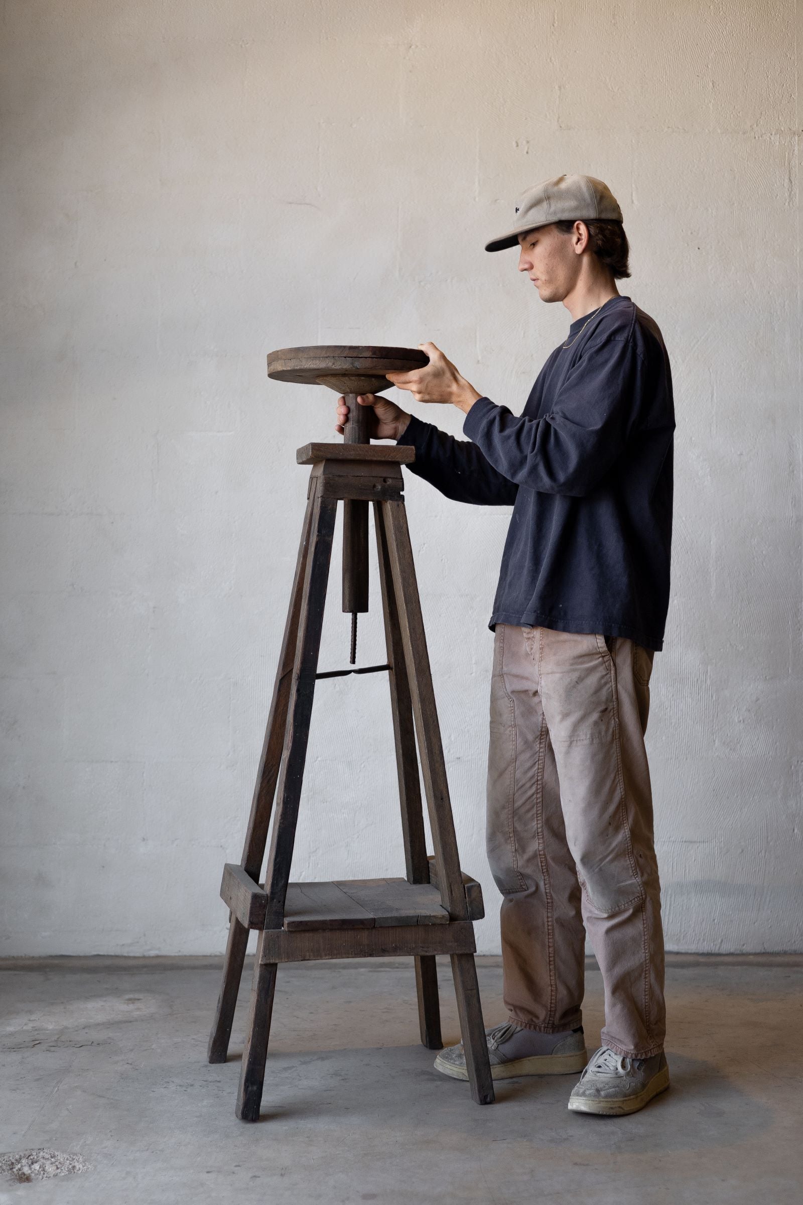 Reclaimed wood sculpture stand with man attaching pedestal to the stand.