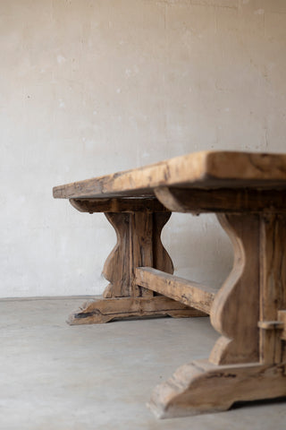 Wooden table with rustic design against a plain wall