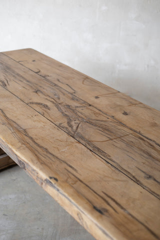 Wooden table with a rustic finish against a plain white wall