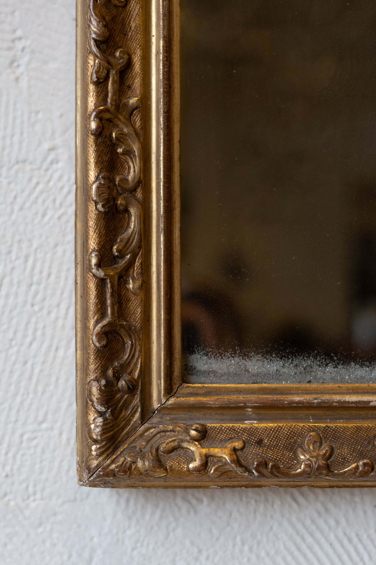 Close-up of an antique mirror's baroque gold frame design. 
