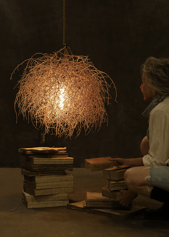 a woman sitting on a floor next to a pile of books