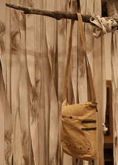 a bag hanging from a wooden branch in front of a curtain